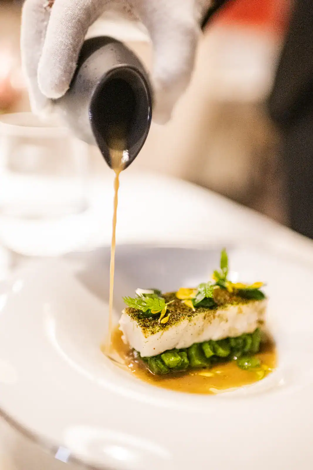 Sauce wird über ein Fischgericht gegossen, Restaurant Tilia in Toblach