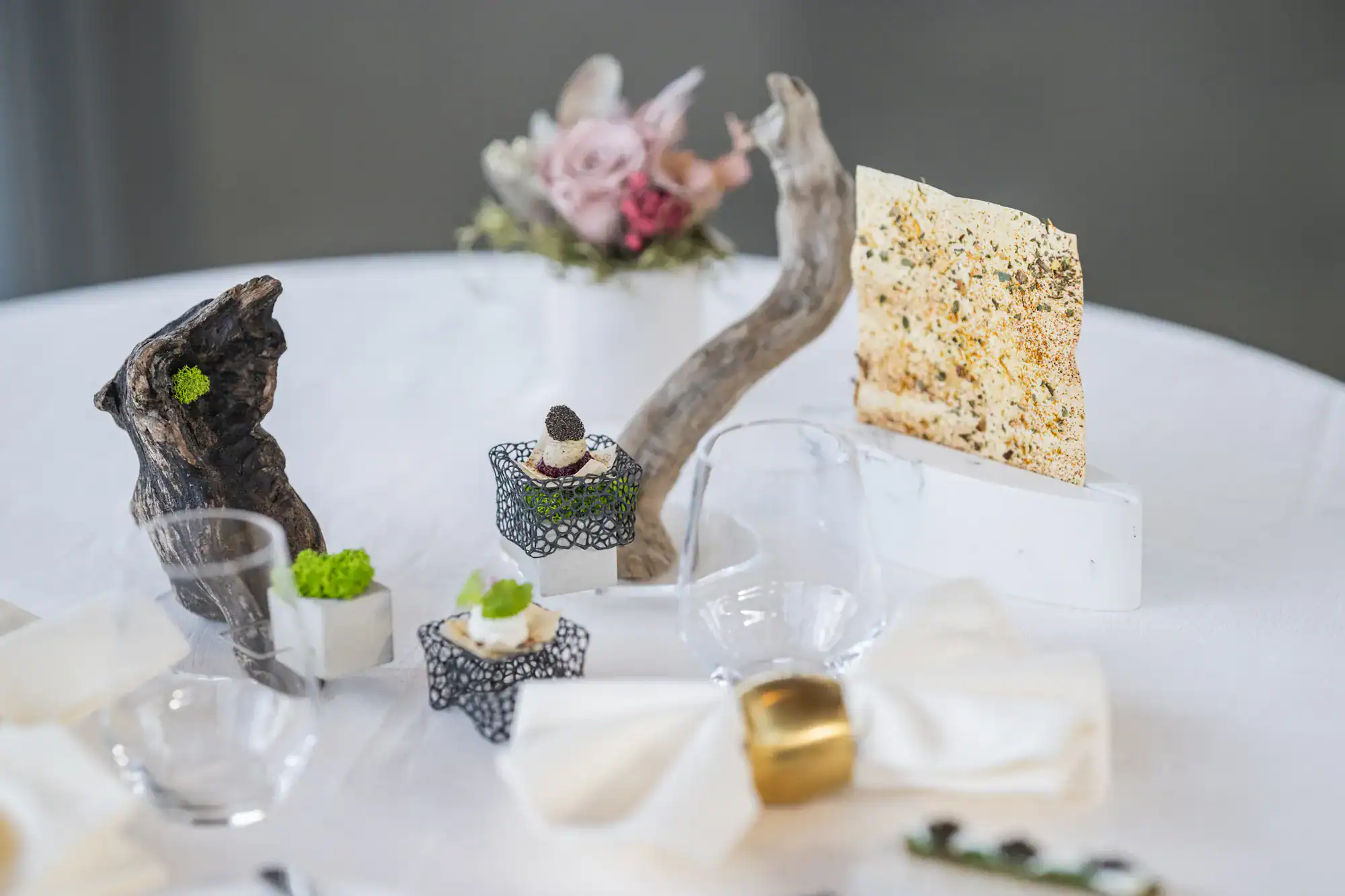 Gedeckter Tisch im Restaurant Tilia mit Blüten, Holz und kleinen Gängen